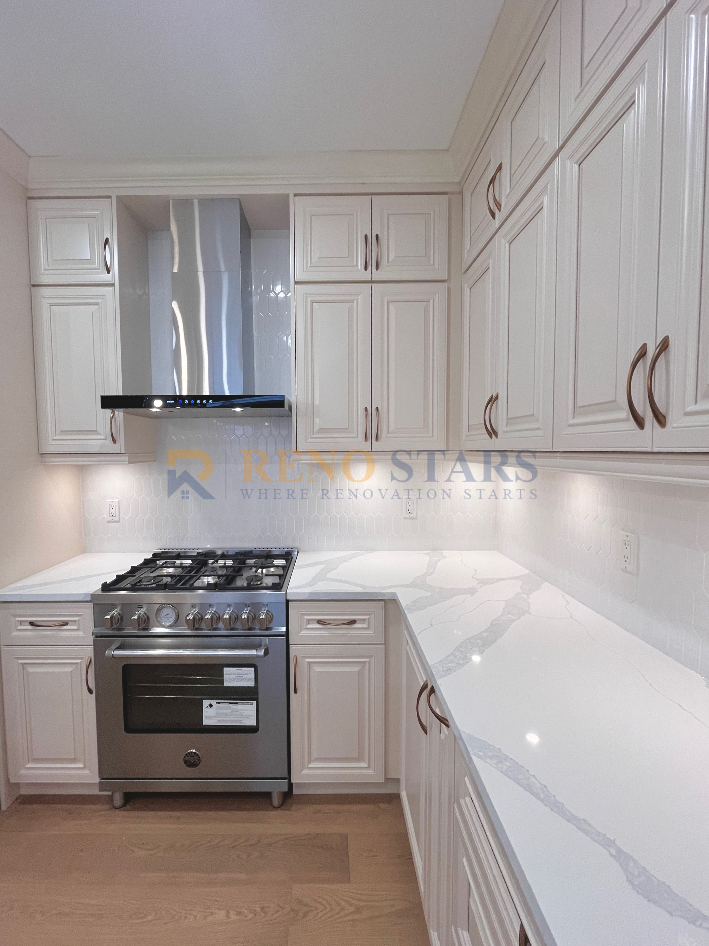 Modern kitchen with white cabinetry, marble countertops, and stainless steel appliances.