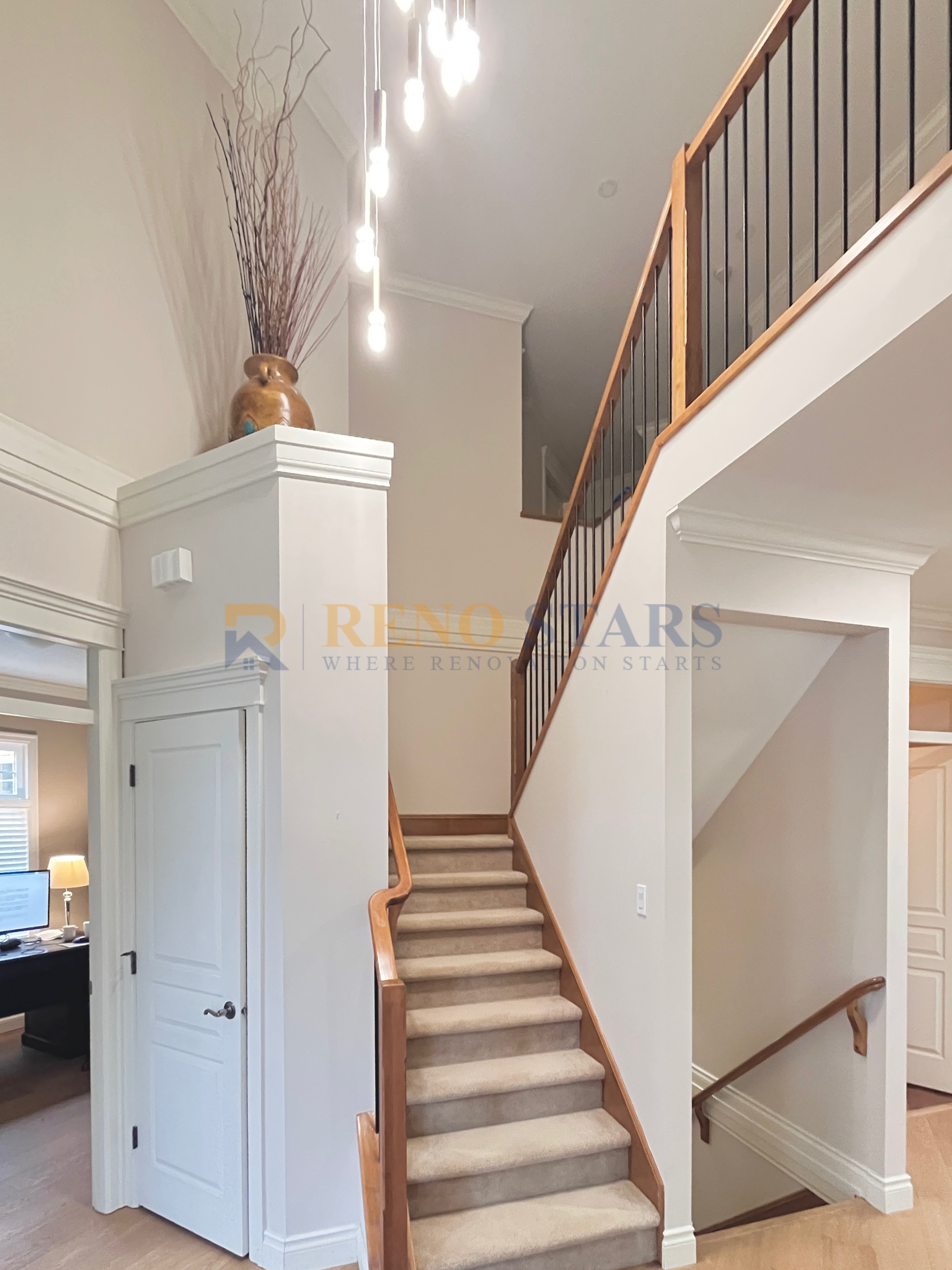 Bright entryway featuring a staircase, decorative vase, and modern lighting fixtures.