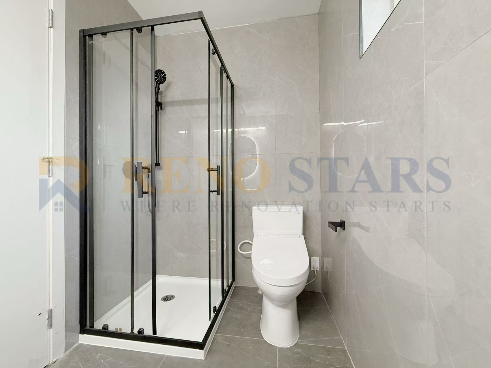 Modern bathroom featuring a glass shower enclosure and sleek toilet on gray tiled floor.
