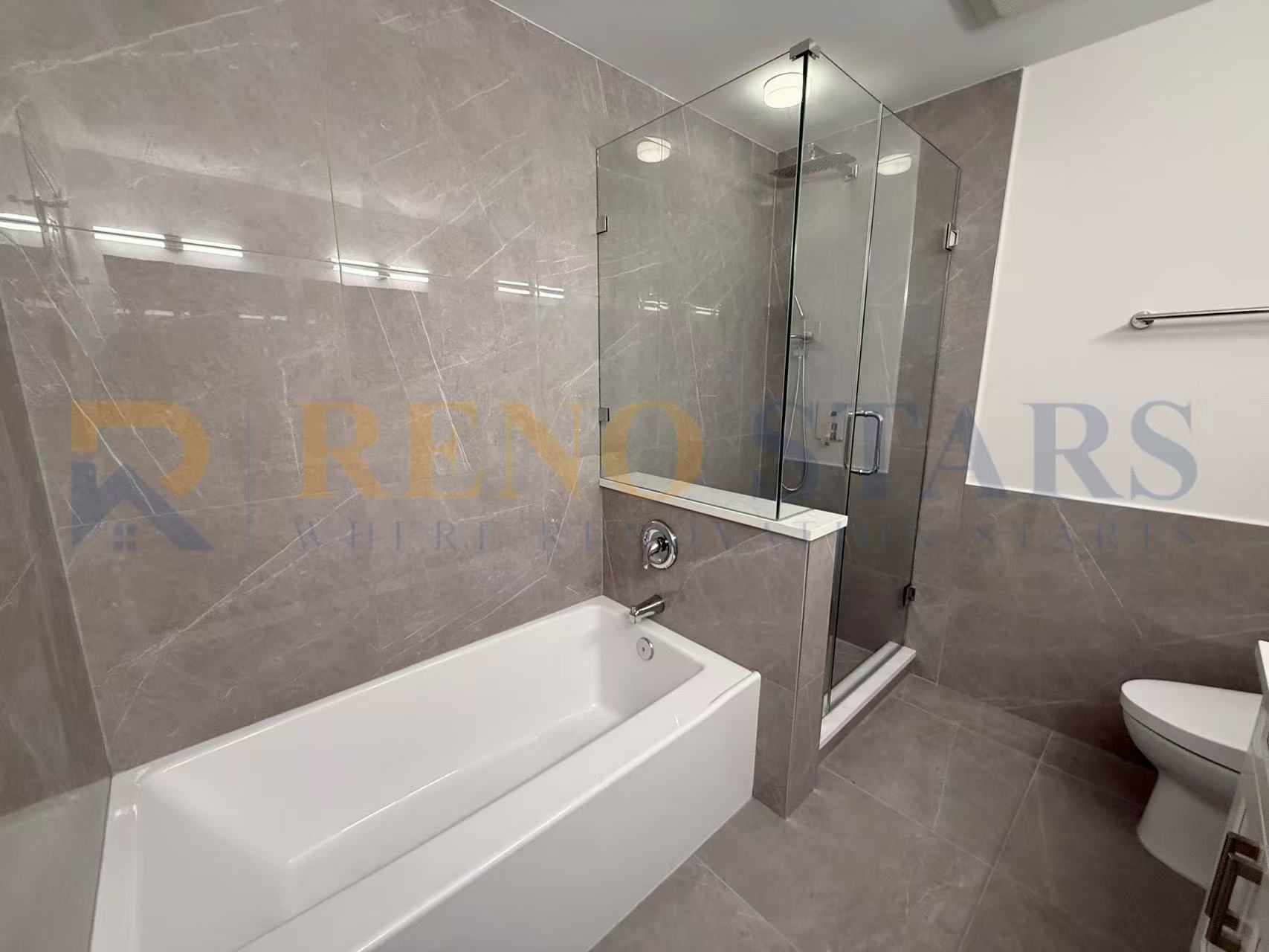 Modern bathroom featuring a glass shower, bathtub, and sleek gray tile walls.