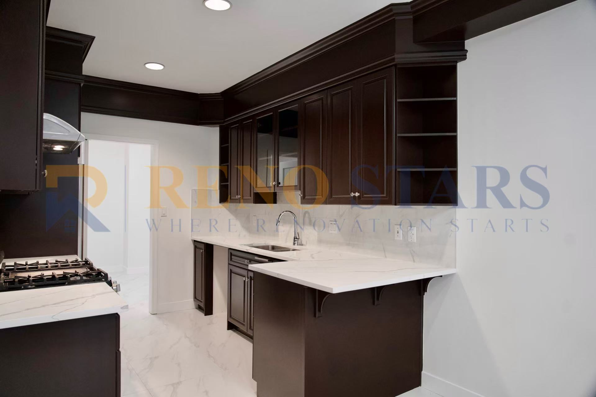 Modern kitchen with dark cabinetry, marble countertops, and stainless steel appliances.