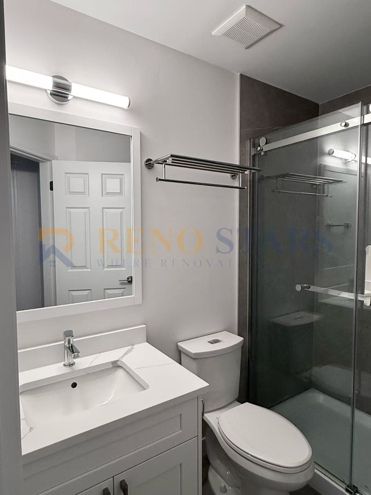 Modern bathroom featuring a glass shower, sleek vanity, and bright lighting.