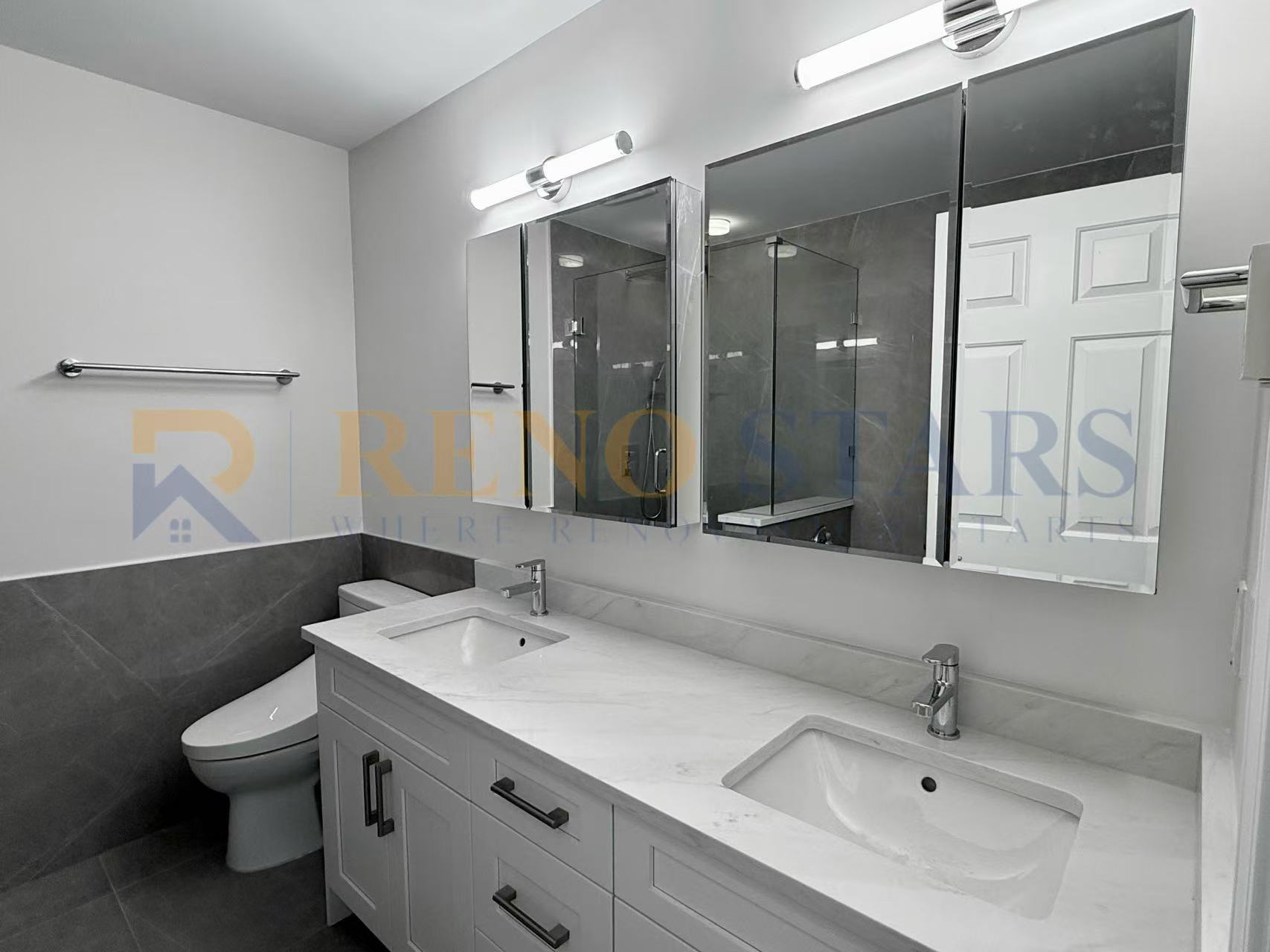 Modern bathroom featuring dual sinks, large mirrors, and sleek gray tile accents.
