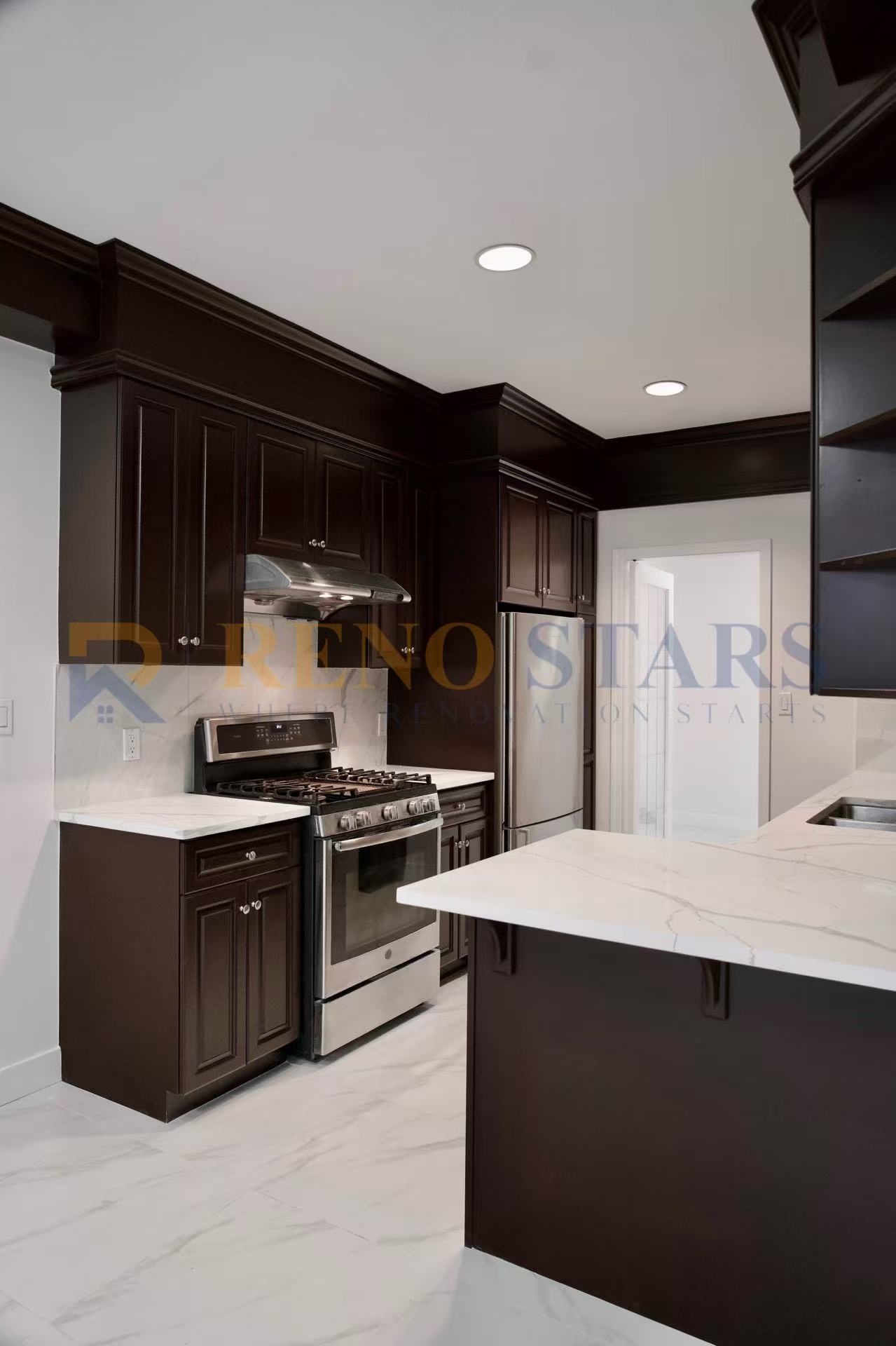 Modern kitchen featuring dark cabinetry, stainless steel appliances, and marble countertops.