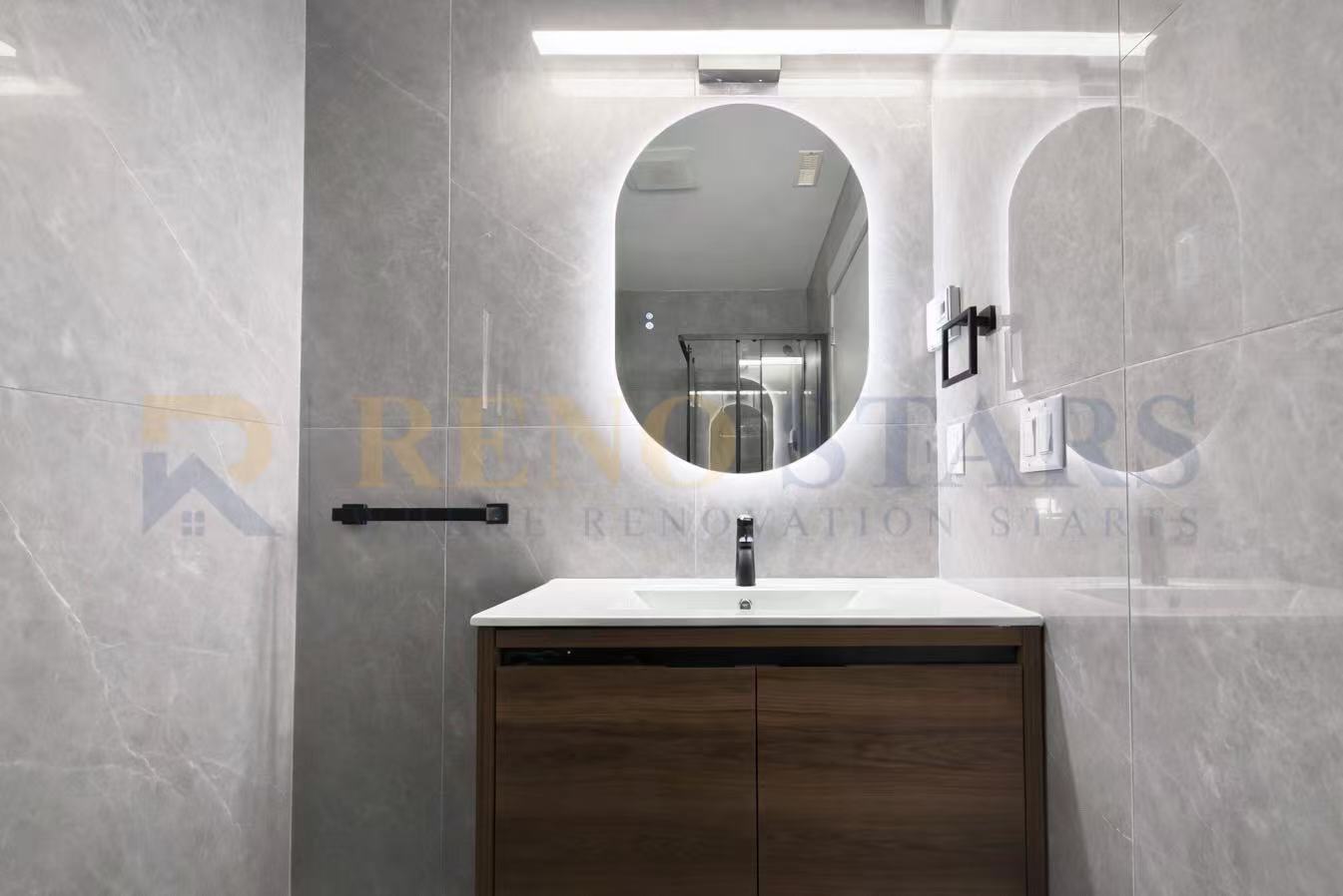 Modern bathroom featuring a sleek vanity, oval mirror, and stylish gray tiles.